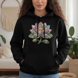May include: Black hoodie featuring a colorful lotus flower design. The lotus is detailed with pink, blue, green, and yellow patterns. The hoodie has a drawstring hood and a front pocket. The design is centered on the chest.