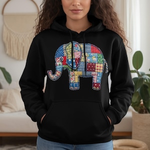 Puede incluir: Sudadera con capucha negra con un diseño de elefante patchwork. El elefante está compuesto por varios patrones de tela, incluyendo floral, lunares y cuadros. La sudadera tiene un bolsillo delantero y una capucha con cordón.