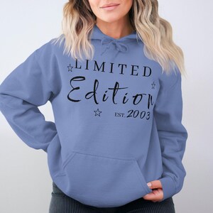 Könnte beinhalten: Ein hellblauer Kapuzenpullover mit dem Text "LIMITED EDITION EST. 2003" in schwarzer Schrift. Der Text ist von kleinen schwarzen Sternen umgeben.