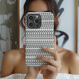 May include: A white iPhone case with a black geometric pattern. The design features horizontal rows of various shapes, including lines, dashes, and curves. The case has a glossy finish and covers the back and sides of the phone.