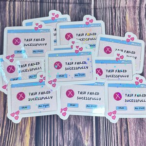Puede incluir: Un conjunto de pegatinas holográficas con un diseño de mensaje de error de computadora. Cada pegatina presenta una ventana azul claro con el texto "TASK FAILED SUCESSFULLY", un icono "X" rojo y las frases "OKAY" y "AW, FUCK". Corazones rosas decoran los bordes.