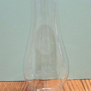 May include: A clear glass lamp chimney with a rounded bottom and a straight top.