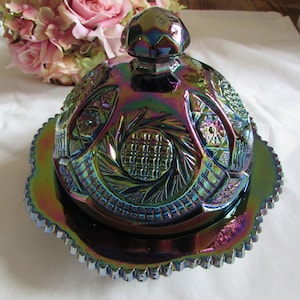 Könnte beinhalten: Eine vintage irisierende Glasbutterdose mit einem gewölbten Deckel und einem gewellten Rand. Die Schale hat ein wirbelndes Muster und ist in den Farben Lila, Blau und Grün gehalten.