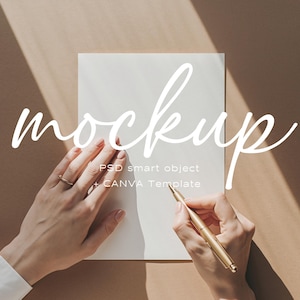 May include: A mockup scene featuring a blank white card with the word "mockup" in a cursive font. A person's hands are holding a gold pen, ready to write. The background is a warm, neutral tone.