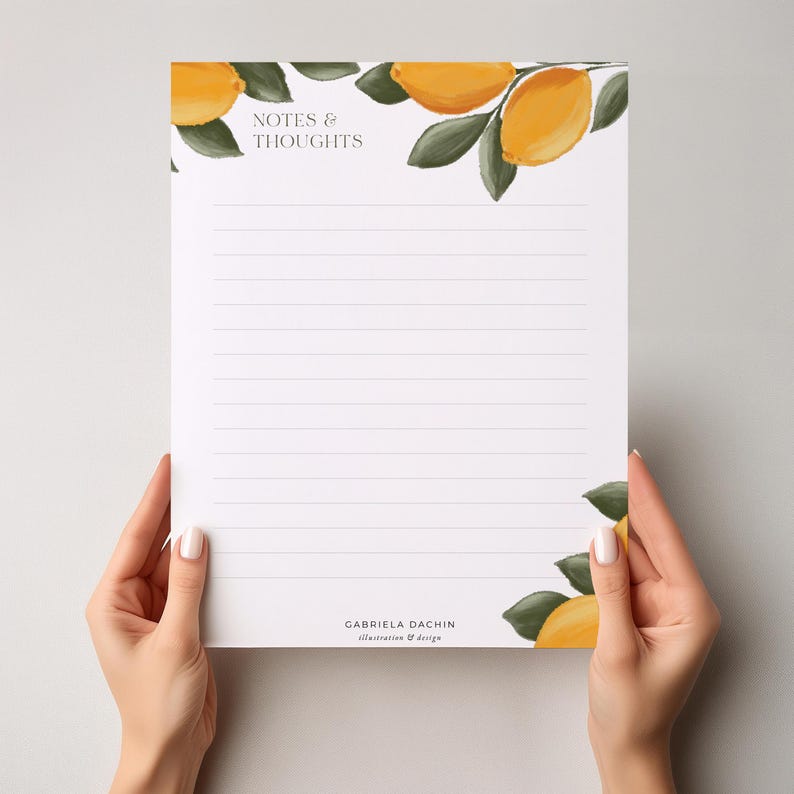 May include: A white notepad with lined pages, held by hands. The notepad features watercolor illustrations of lemons and leaves, with the text "NOTES & THOUGHTS" at the top and the designer's name at the bottom.