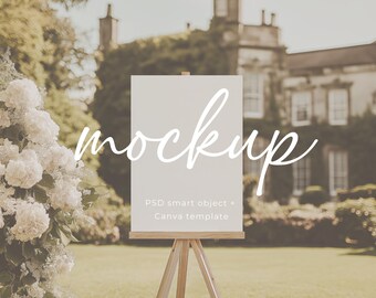 May include: A white easel with a blank canvas sign in front of a green lawn and a large stone building in the background. The sign says "mockup" in cursive writing. The text below the sign says "PSD smart object - Canva template".