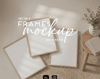 Puede incluir: Una maqueta con tres marcos rectangulares con bordes de madera clara, dispuestos sobre una superficie beige texturizada. Los marcos están en ángulo, mostrando espacios en blanco. El texto dice "SET OF 3 FRAMES mockup DIN A RATIO". Una pequeña mesa con un jarrón y libros está en el fondo.