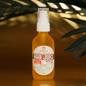 May include: A clear glass bottle filled with amber liquid, labelled "Hair Juice" by "Sunny Soil." The label lists ingredients and a "Made in USA" emblem. The bottle has a white spray nozzle and contains 59 ml of product.
