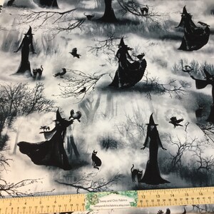 May include: Fabric with a spooky Halloween theme. The design features black silhouettes of witches, cats, and crows against a misty, grayscale forest backdrop. The fabric includes the text "Sassy and Chic Fabrics etsy.com".
