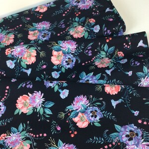 May include: Dark navy fabric with a floral pattern. The design features bouquets of pink, purple, and blue flowers with green leaves. The fabric is folded, showing the pattern's repeat.
