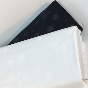 May include: Two rolls of fabric, one white and one black. The white fabric features a pattern of stars, birds, and hearts. The black fabric has a similar design. The rolls are stacked on top of each other.