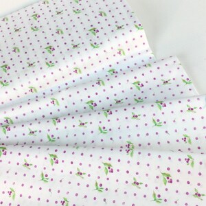 Puede incluir: Papel de seda blanco con un patr&oacute;n repetido de lunares morados y peque&ntilde;as hojas verdes con bayas moradas. El papel est&aacute; doblado, mostrando m&uacute;ltiples capas.
