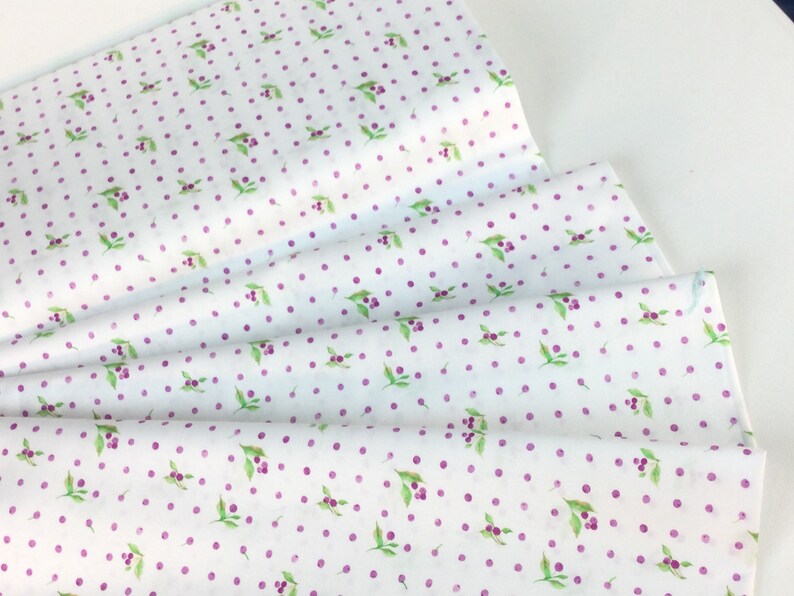 Puede incluir: Papel de seda blanco con un patr&oacute;n repetido de lunares morados y peque&ntilde;as hojas verdes con bayas moradas. El papel est&aacute; doblado, mostrando m&uacute;ltiples capas.