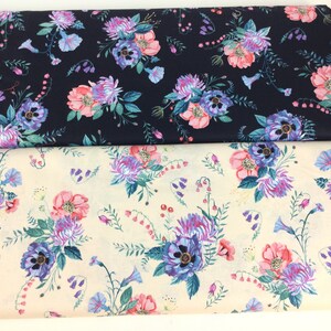 May include: Two rolls of floral fabric. One is navy blue, the other is cream. Both feature a repeating pattern of pink, purple, and blue flowers with green leaves. The fabric is likely cotton or a similar material.