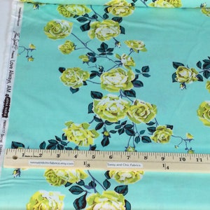 May include: A fabric with a light blue background featuring a floral pattern of yellow roses and dark green leaves. The fabric includes the text "Love Always, AM" and "Sassy and Chic Fabrics". A ruler shows measurements in inches.