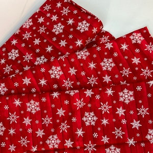 Pu&ograve; includere: Tessuto rosso con un motivo a fiocchi di neve bianchi. Il tessuto ha una trama a venature di legno ed &egrave; piegato a strati. I fiocchi di neve variano per dimensioni e design, creando un tema invernale festoso.