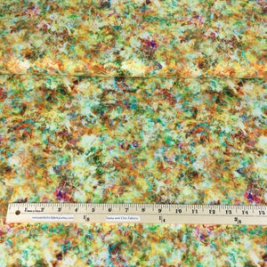 May include: Fabric with a colorful abstract design. The fabric features a mix of yellow, green, orange, and purple hues. A ruler with inch measurements is placed on the fabric. The text "Sassy and Chic Fabrics" is visible.