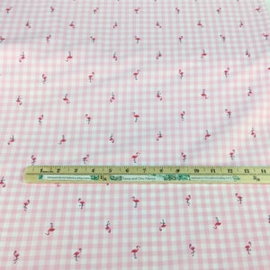 Puede incluir: Tela de cuadros rosa y blanco con un estampado de peque&ntilde;os flamencos rosas. Una regla de madera con medidas en pulgadas est&aacute; colocada sobre la tela. La tela es adecuada para proyectos de costura y manualidades.