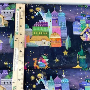 Puede incluir: Tela con un dise&ntilde;o colorido con tem&aacute;tica navide&ntilde;a. La tela presenta ilustraciones de edificios, &aacute;ngeles, estrellas y un pesebre. La paleta de colores incluye azul, morado, verde, naranja y amarillo. Una regla de madera est&aacute; colocada sobre la tela.