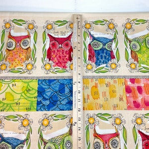 May include: Fabric panel featuring colorful owl illustrations within floral frames. The owls have various patterns and colors, including red, blue, and green. The panel also includes patterned blocks below the owls. The ruler shows the panel is approximately 15 inches long.
