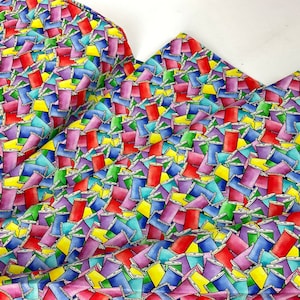 May include: Fabric with a colorful pattern of spools of thread in various colors, including red, purple, blue, yellow, and green. The spools are arranged in a dense, overlapping design, creating a vibrant and playful textile.