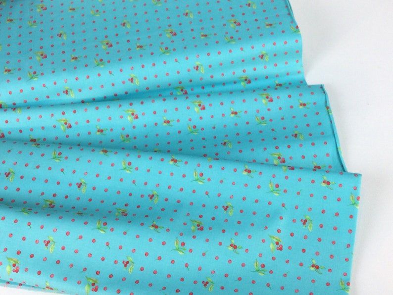 Puede incluir: Tela turquesa con un patr&oacute;n repetido de cerezas rojas y hojas verdes. La tela est&aacute; doblada, mostrando la textura y el dise&ntilde;o. Ideal para proyectos de acolchado, costura o manualidades.