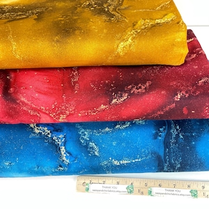 May include: A stack of fabric in gold, red, and blue with a marbled design. The fabric has a metallic sheen and a ruler is at the bottom. The text on the ruler says "Thank You" and the Etsy shop name.