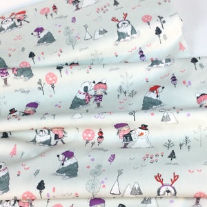 May include: Light blue fabric with a winter scene print. The design features children, dogs, snowmen, trees, and mountains in shades of gray, pink, and purple. The fabric is folded, showing the pattern's repeat.