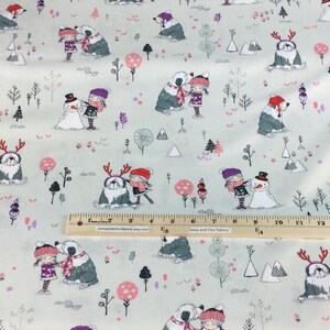 May include: Light gray fabric with a winter-themed pattern. The design features illustrations of children, snowmen, dogs, trees, and mountains in shades of gray, pink, and purple. The fabric is suitable for various sewing projects.