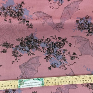 Puede incluir: Tela rosa con un patr&oacute;n repetido de murci&eacute;lagos, telara&ntilde;as y elementos florales en negro y morado claro. Medici&oacute;n en cent&iacute;metros.