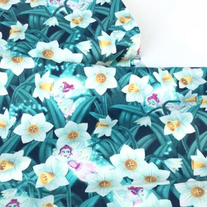 May include: Fabric with a repeating pattern of white daffodils with yellow centers and green leaves on a dark teal background. The design includes small fairy illustrations with pink and purple accents.