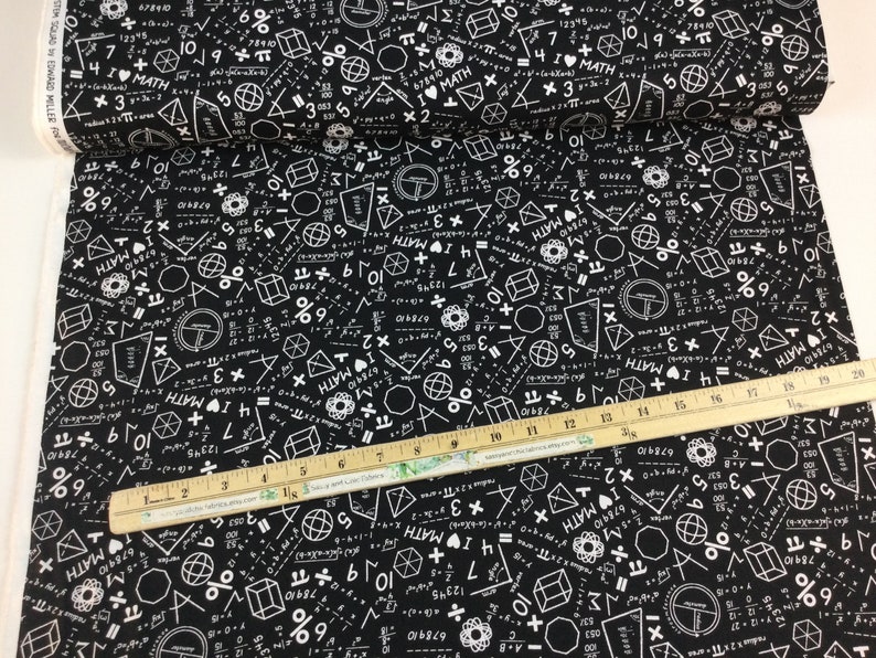 May include: Black fabric printed with white math symbols, equations, and the words "I MATH." Geometric shapes and numbers are scattered across the fabric. A wooden ruler with inch markings is placed on the fabric.