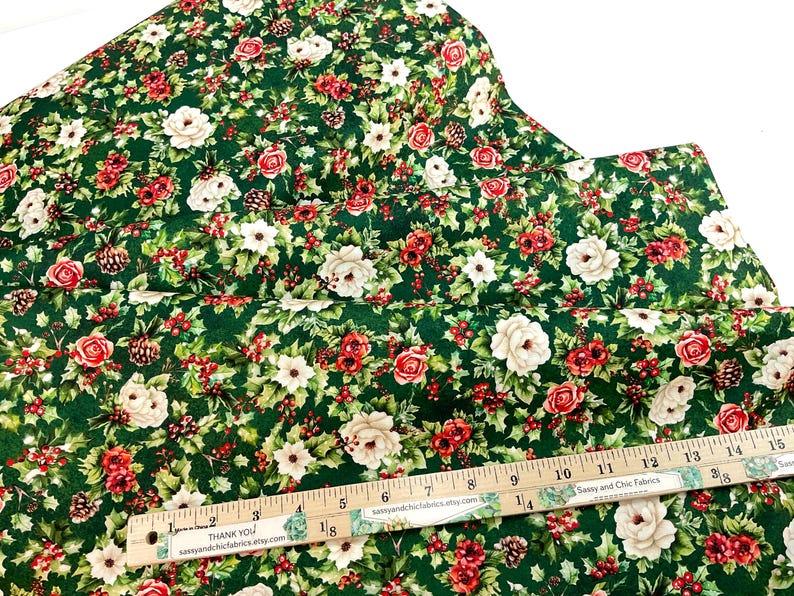 K&ouml;nnte beinhalten: Gr&uuml;ner Stoff mit floralem Muster mit roten Rosen, wei&szlig;en Bl&uuml;ten und Tannenzapfen. Ein Holzlineal mit Zentimetermarkierungen liegt auf dem Stoff. Der Text "THANK YOU" und "sassyandchicfabrics.etsy.com" ist sichtbar.