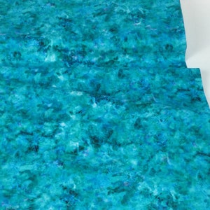 May include: A close-up of a fabric with a watercolor-like pattern in shades of teal, turquoise, and blue. The fabric has a textured appearance, with areas of darker and lighter hues creating a sense of depth and movement. The fabric is folded.