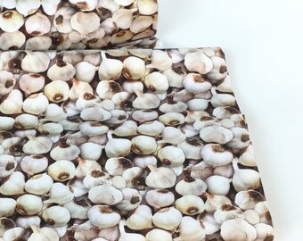 Könnte beinhalten: Stoff mit einem sich wiederholenden Muster aus Knoblauchzehen in Weiß-, Beige- und Brauntönen. Der Stoff ist gefaltet und zeigt das Muster auf der Ober- und Seite. Der Hintergrund ist schlicht weiß.