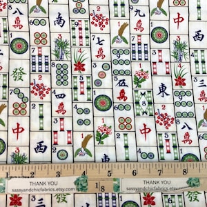 May include: Mahjong fabric with a repeating pattern of tiles featuring Chinese characters, bamboo, and floral designs in red, green, and black on an off-white background. A wooden ruler is at the bottom.
