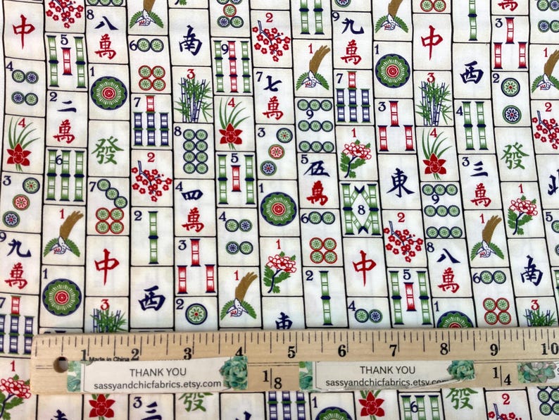 May include: Mahjong fabric with a repeating pattern of tiles featuring Chinese characters, bamboo, and floral designs in red, green, and black on an off-white background. A wooden ruler is at the bottom.