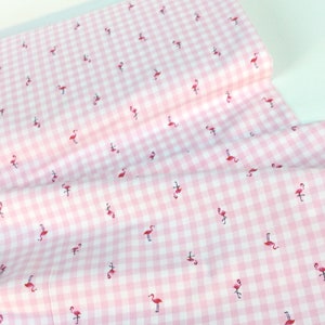 Puede incluir: Tela de cuadros rosa y blanco con un patr&oacute;n repetido de peque&ntilde;os flamencos rojos. La tela est&aacute; doblada, mostrando la textura y el patr&oacute;n del material. Ideal para proyectos de manualidades, costura o decoraci&oacute;n del hogar.