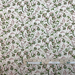 Puede incluir: Tela color crema con un patr&oacute;n repetido de hojas verdes y peque&ntilde;as bayas rojas. Una regla se coloca en la parte inferior, midiendo hasta 35,5 cm. La tela es adecuada para proyectos de costura o manualidades.