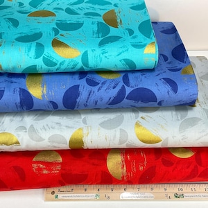May include: A stack of colorful fabric bolts featuring a repeating pattern of gold half-circles on a variety of backgrounds. Colors include turquoise, blue, light blue, white, and red. A wooden ruler is at the bottom.
