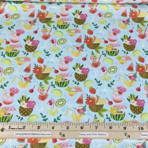 May include: Light blue fabric with a tropical cocktail and fruit pattern. The design includes pineapples, watermelon, strawberries, and lime slices. The fabric has a ruler along the bottom with the text "Sassy and Chic Fabrics".