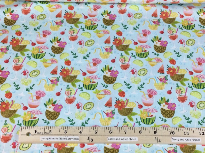 May include: Light blue fabric with a tropical cocktail and fruit pattern. The design includes pineapples, watermelon, strawberries, and lime slices. The fabric has a ruler along the bottom with the text "Sassy and Chic Fabrics".