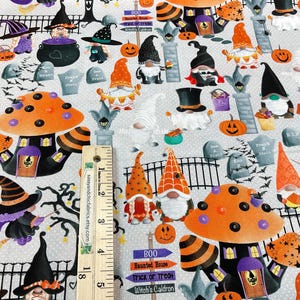 May include: Halloween-themed fabric featuring whimsical gnomes, witch hats, pumpkins, and mushroom houses. The design includes tombstones, bats, and the text "BOO Haunted House Trick or Treat Witch's Caldron". The fabric is light gray with a repeating pattern.
