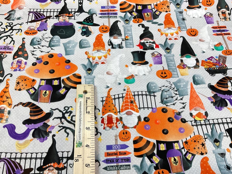 May include: Halloween-themed fabric featuring whimsical gnomes, witch hats, pumpkins, and mushroom houses. The design includes tombstones, bats, and the text "BOO Haunted House Trick or Treat Witch's Caldron". The fabric is light gray with a repeating pattern.