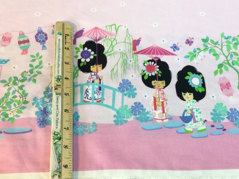 May include: Pink fabric with a repeating pattern of Japanese dolls, bridges, lanterns, and flowers. The dolls have black hair and wear colorful outfits. The design includes a ruler with the text "Sassy and Chic Fabrics".