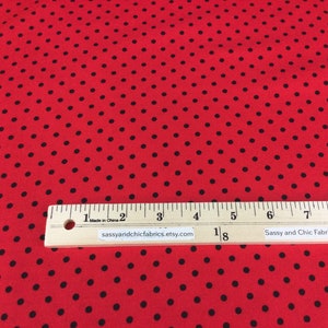 May include: Red fabric with black polka dots. A wooden ruler with inch markings is placed across the fabric. The text "sassyandchicfabrics.etsy.com" is printed on the ruler.