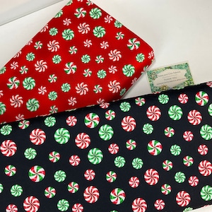 May include: Two fabric samples with a repeating pattern of red, white, and green peppermint candies. One fabric is red, the other is black. A small card with text is visible.