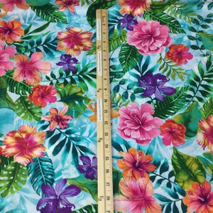 May include: Vibrant floral fabric featuring large pink, orange, and purple hibiscus flowers and tropical leaves on a light blue background. The fabric is decorated with a ruler that measures up to 19 inches.