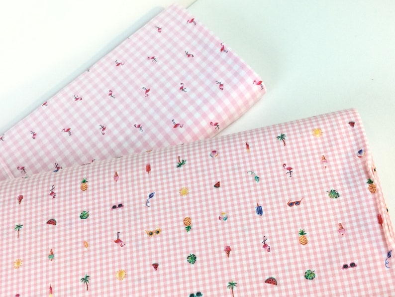 Puede incluir: Dos piezas de tela de cuadros rosa y blanco. Una pieza presenta peque&ntilde;os dise&ntilde;os de flamencos, mientras que la otra tiene una variedad de ilustraciones con temas de verano, incluyendo gafas de sol, helados y palmeras. La tela es ideal para manualidades de verano.