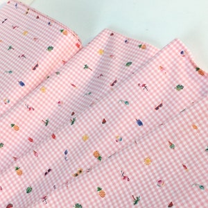 Puede incluir: Tela de cuadros rosa y blanco con un estampado repetido de ilustraciones de verano. El dise&ntilde;o incluye gafas de sol, flamencos, pi&ntilde;as, palmeras, helados y pelotas de playa. La tela est&aacute; doblada, mostrando la repetici&oacute;n del patr&oacute;n.